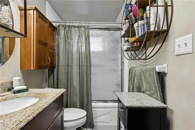 a bathroom with a granite countertop sink toilet and shower