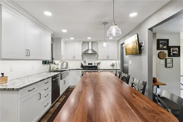 a large kitchen with stainless steel appliances granite countertop a lot of counter space and wooden floors