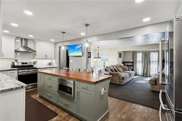 a kitchen with kitchen island a counter top space a sink stainless steel appliances and cabinets