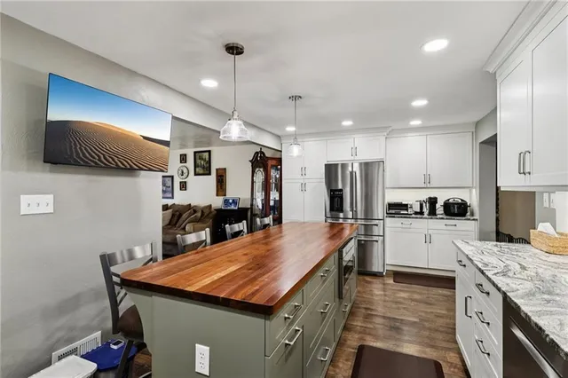 a kitchen with stainless steel appliances kitchen island granite countertop a kitchen island a stove and a sink