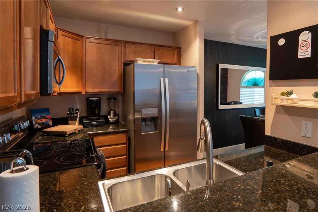 9325 West Desert Inn Road, Unit 264 Las Vegas, NV 89117 - Photo 4 of 10 Rich wood cabinetry paired with dark granite countertops enhances this efficient kitchen space.
