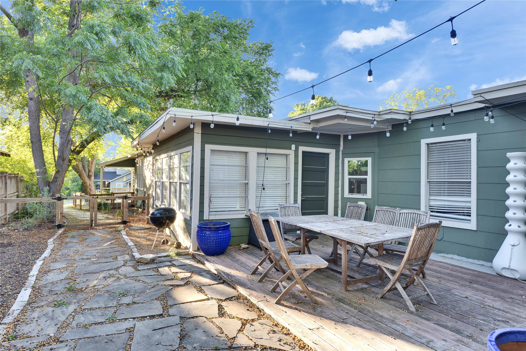 4607 Evans Avenue, Unit B Austin, TX 78751 - Photo 4 of 34 Exterior featuring a wood-finish deck with string lighting, flagstone pathway, wood fencing, and mature trees