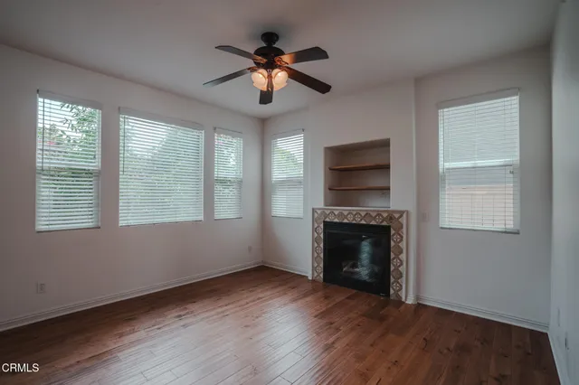 a view of an empty room with wooden floor fireplace and a window