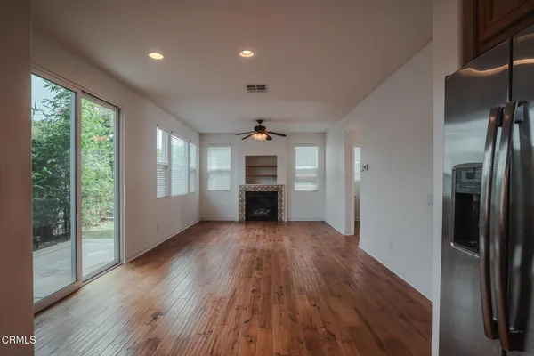 an empty room with wooden floor fireplace and windows
