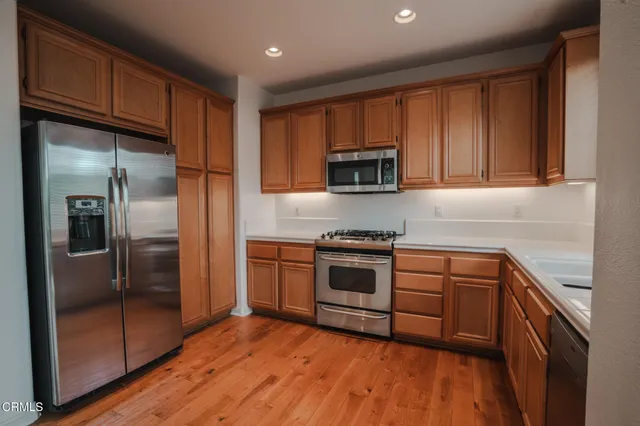 a kitchen with stainless steel appliances granite countertop a refrigerator a sink and a stove