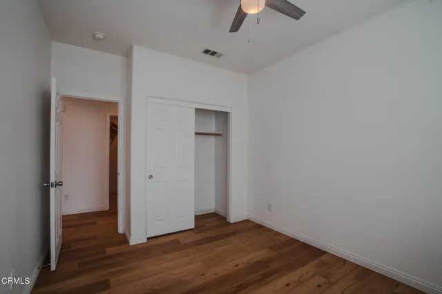an empty room with wooden floor and a ceiling fan