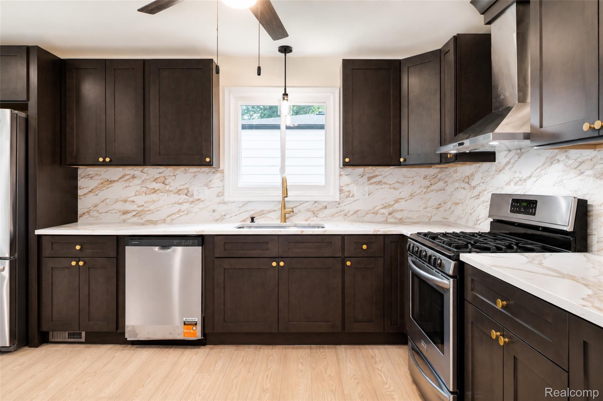 201 Cardwell Street Inkster, MI 48141 - Photo 11 of 41 Kitchen featuring dark wood cabinetry with gold-tone hardware, white countertops, and a white and gold patterned backsplash