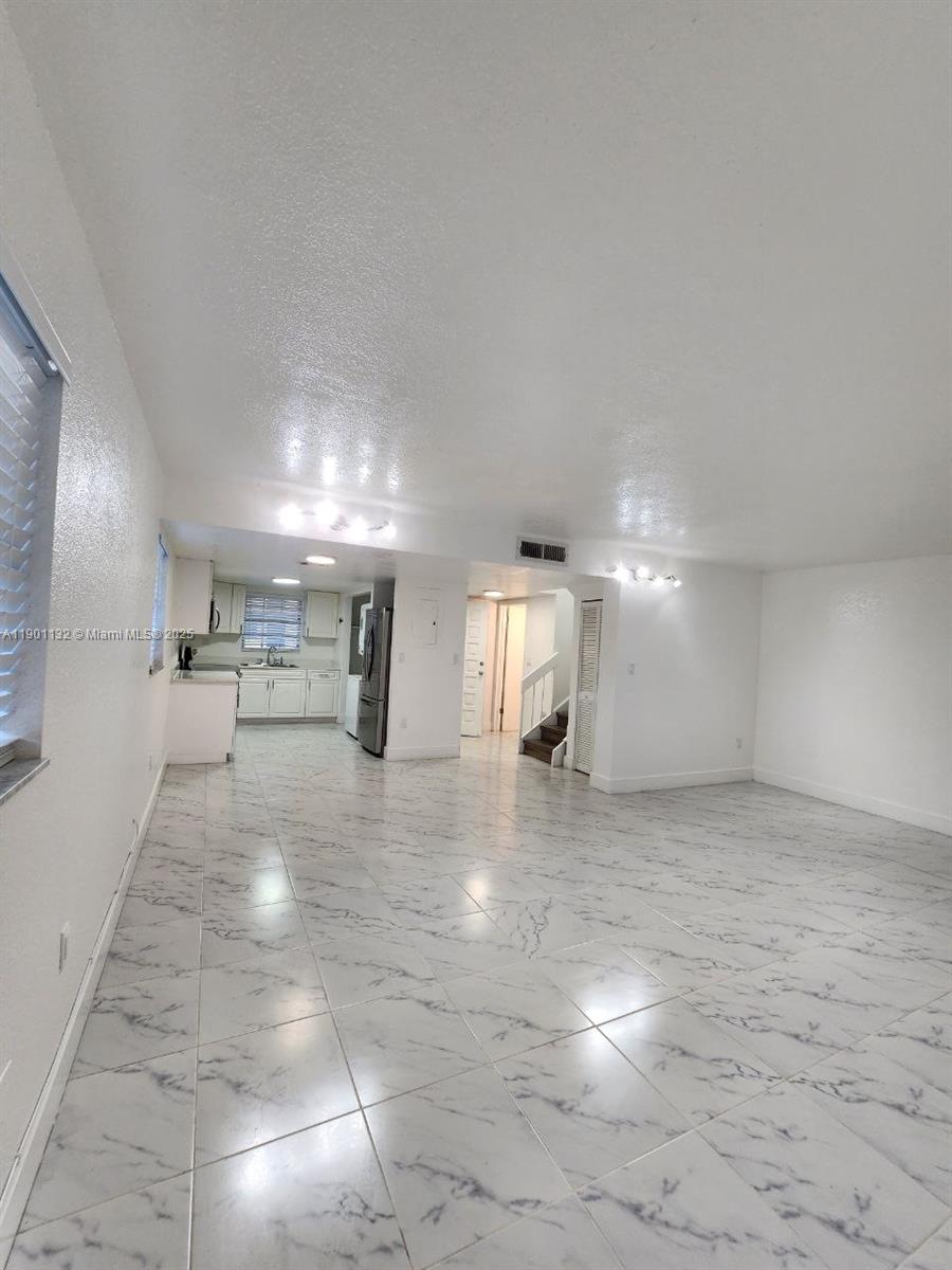 5100 West 12th Lane, Unit E7 Hialeah, FL 33012 - Photo 14 of 35 a view of a hallway to room with window and wooden floor