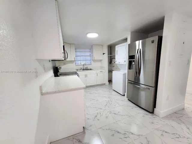 a kitchen with a refrigerator a sink and white cabinets