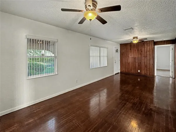 a view of empty room with wooden floor and fan