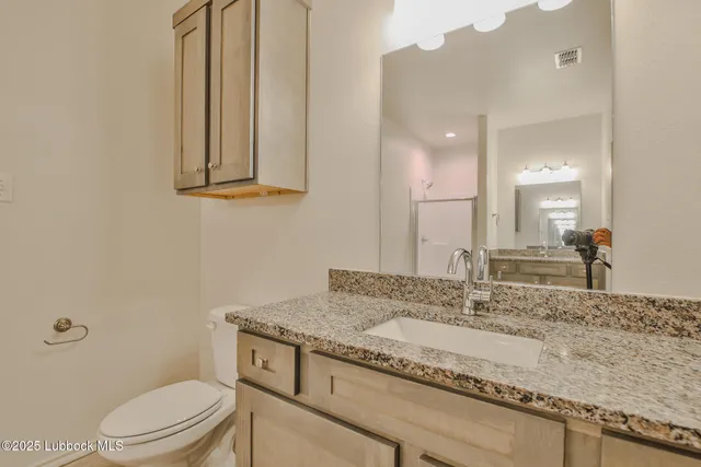 a bathroom with a granite countertop sink and a toilet