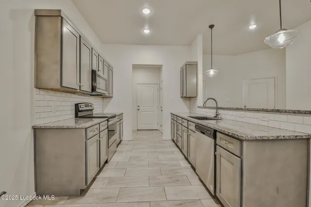a large kitchen with granite countertop a sink and a stove
