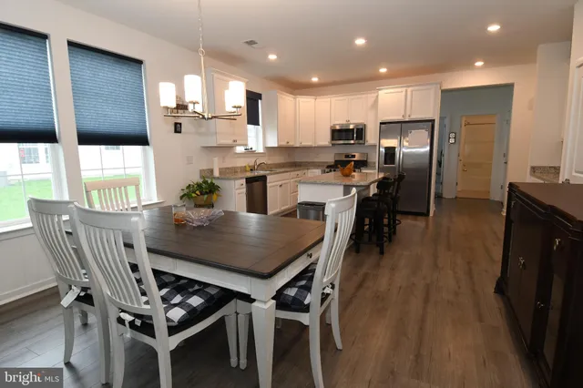 a kitchen with stainless steel appliances kitchen island granite countertop a dining table chairs refrigerator and sink