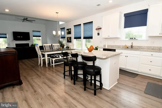 a kitchen with stainless steel appliances granite countertop a table chairs sink and cabinets