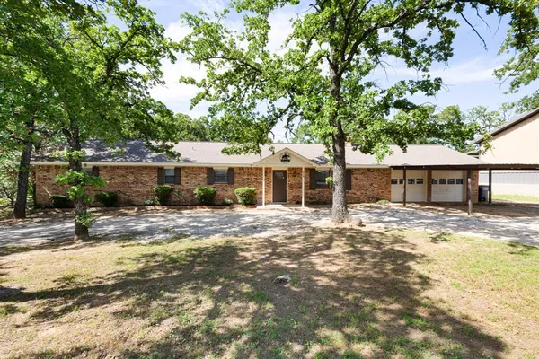 a front view of a house with a large tree