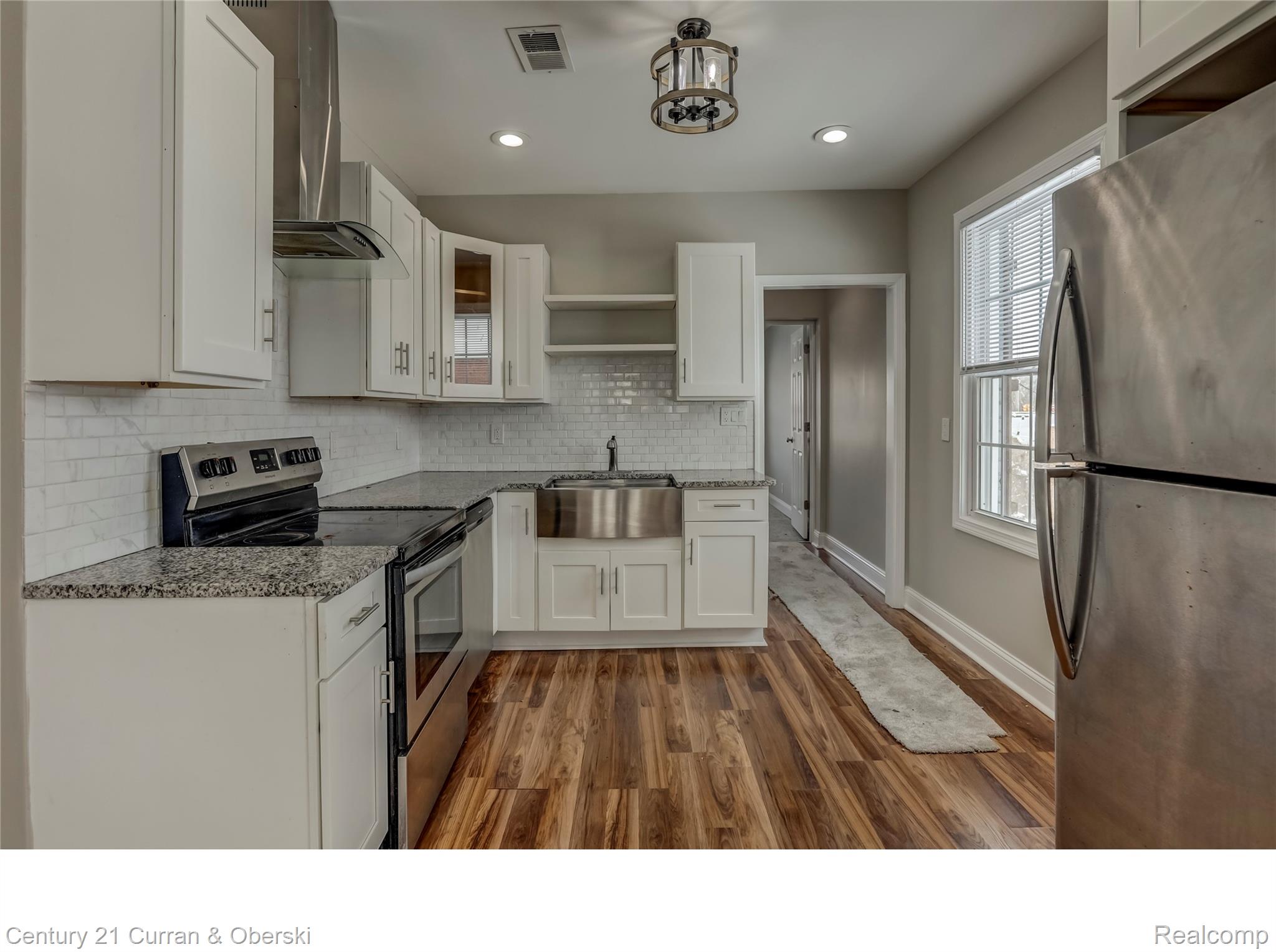 641 Josephine Street Detroit, MI 48202 - Photo 6 of 11 Kitchen featuring white cabinetry, wood-finish flooring, stainless steel appliances, granite-style countertops, and a subway tile backsplash