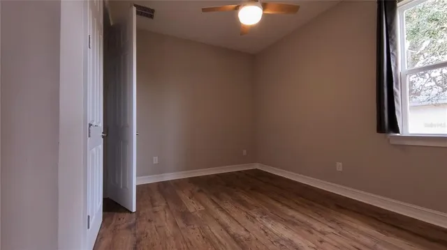 an empty room with wooden floor and windows