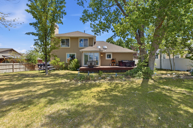 5788 Walden Ridge Drive Murray, UT 84123 - Photo 27 of 29 Spacious rear yard with a two-story stucco exterior, a large wooden deck, multiple mature trees, and a ground-level patio space