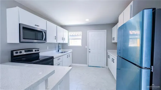 a kitchen with stainless steel appliances a stove a sink and a refrigerator