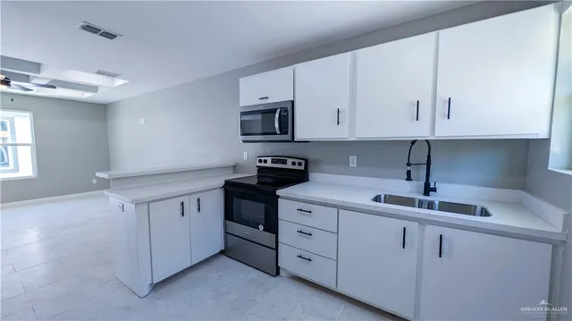 a kitchen with cabinets appliances a sink and a window
