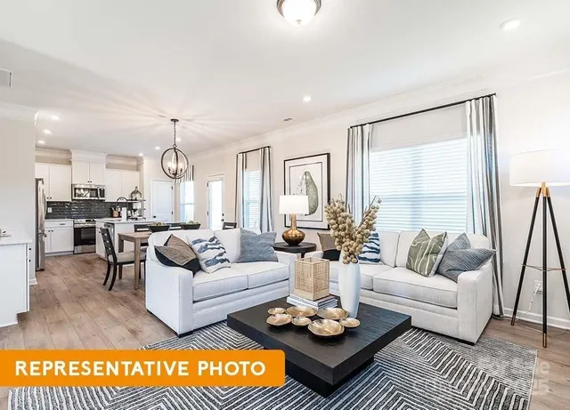 a living room with furniture kitchen view and a large window