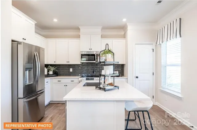 a kitchen with stainless steel appliances a refrigerator a sink a stove a dining table and chairs