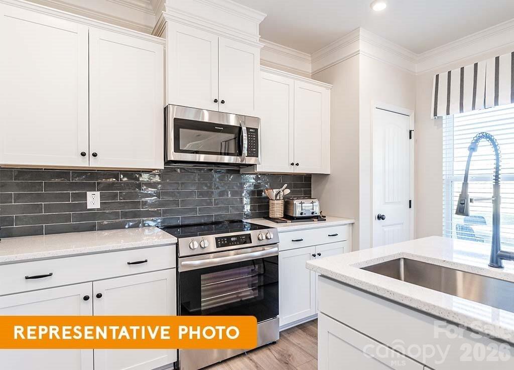 5423 Arnold Way Concord, NC 28025 - Photo 10 of 19 a kitchen with granite countertop a sink a stove and microwave