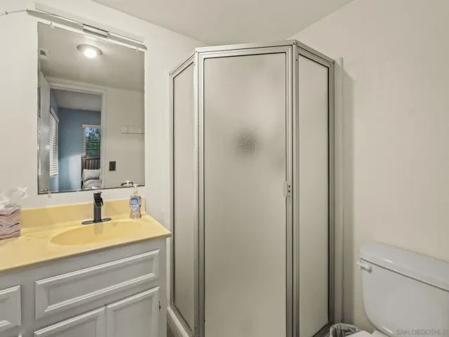 a bathroom with a granite countertop sink vanity mirror and toilet