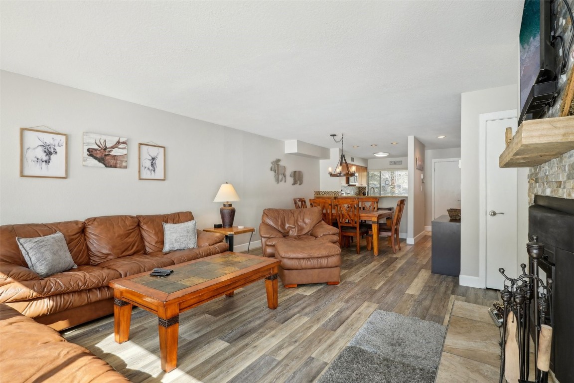 1944 Soda Ridge Road, Unit 1228 Keystone, CO 80435 - Photo 7 of 46 Living area featuring a chandelier, a fireplace, baseboards, and wood finished floors