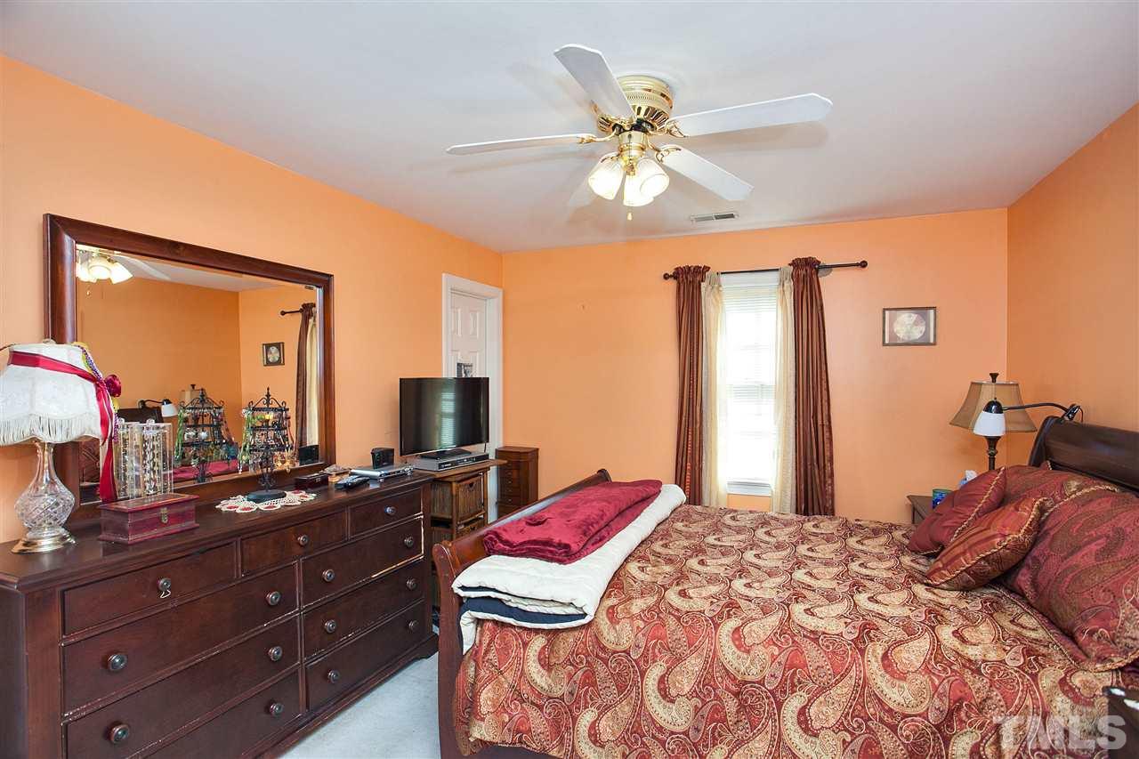 7021 Sandringham Court Raleigh, NC 27613 - Photo 15 of 25 a bedroom with a bed and a chandelier