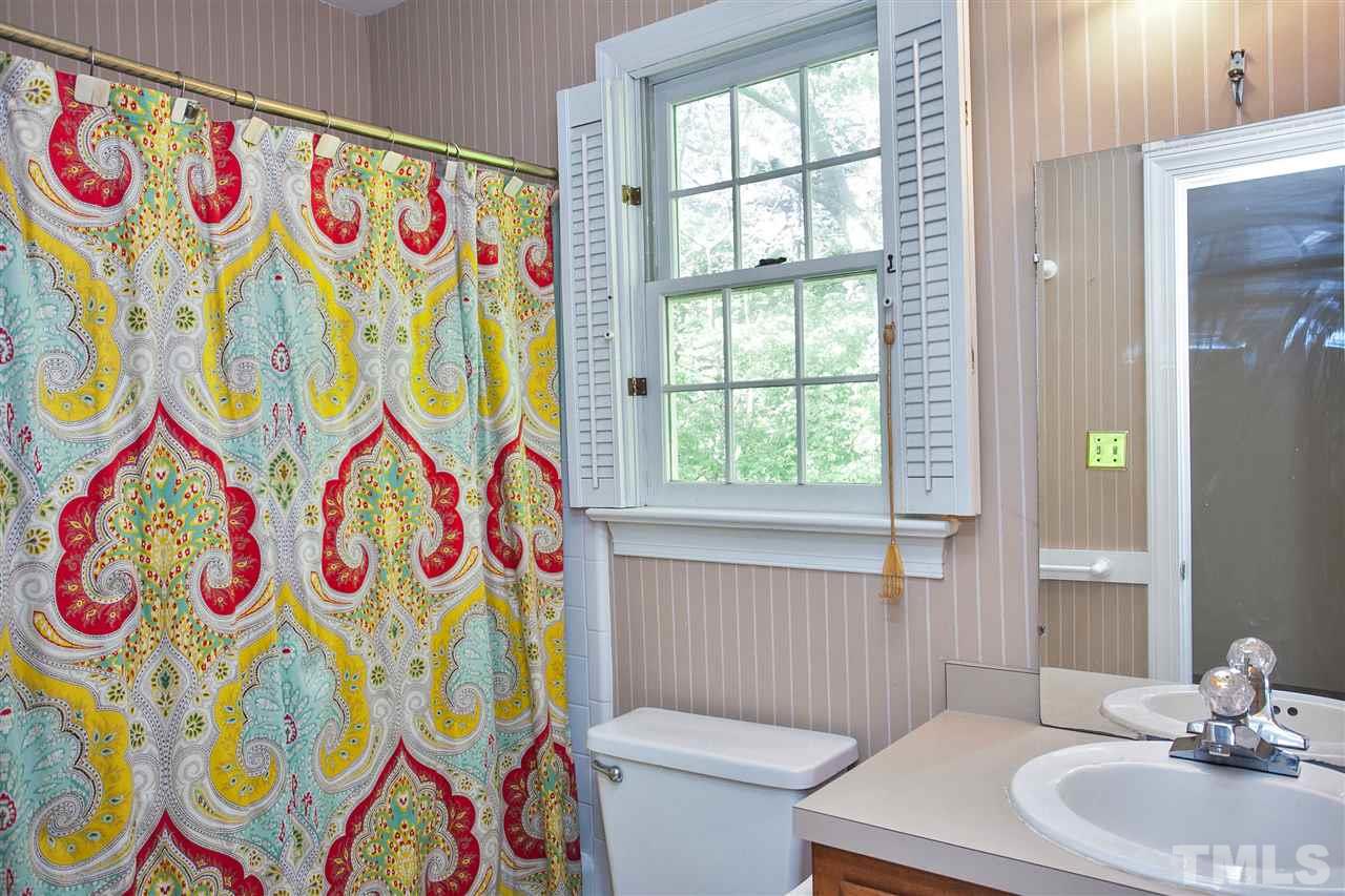 7021 Sandringham Court Raleigh, NC 27613 - Photo 17 of 25 a bathroom with a sink a toilet and a curtain next to a window