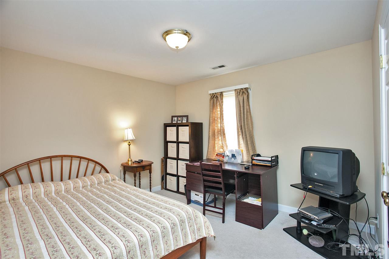 7021 Sandringham Court Raleigh, NC 27613 - Photo 19 of 25 a bedroom with a bed a desk and chair with the floor