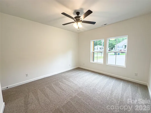 an empty room with windows and ceiling fan