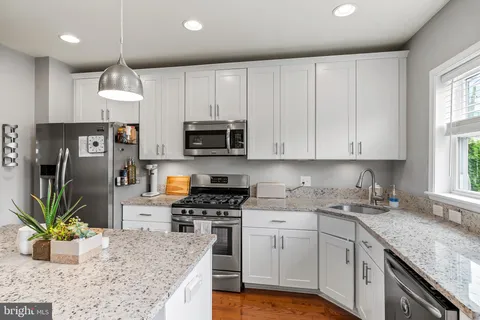 a kitchen with stainless steel appliances granite countertop a stove top oven a sink dishwasher a dining table and chairs with wooden floor