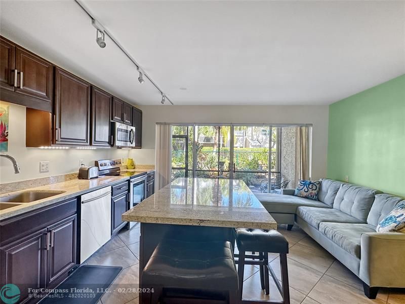 a living room with stainless steel appliances granite countertop furniture and a kitchen view