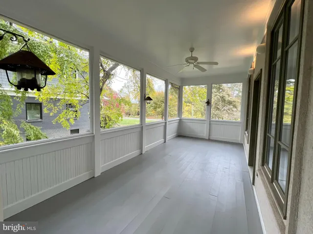 a view of a room with wooden floor ceiling fan and window
