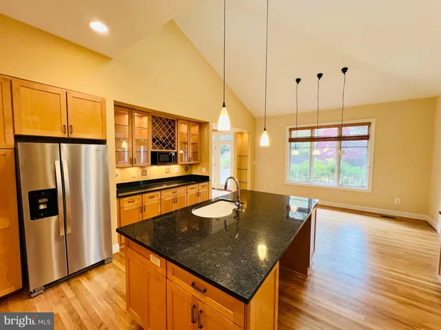 a large kitchen with stainless steel appliances kitchen island granite countertop a refrigerator and a stove top oven