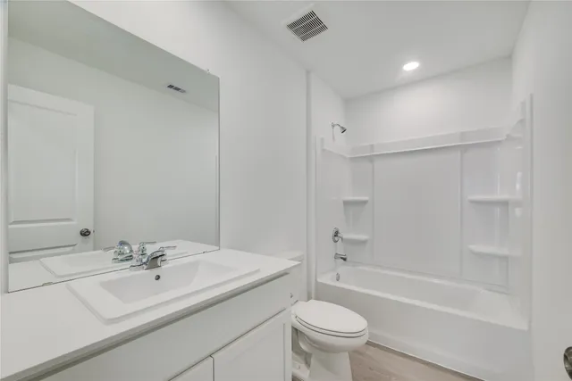 a bathroom with a bathtub shower sink vanity and toilet