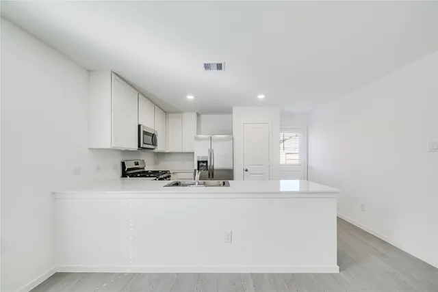 a kitchen with stainless steel appliances a sink a stove a microwave a refrigerator a center island and cabinets