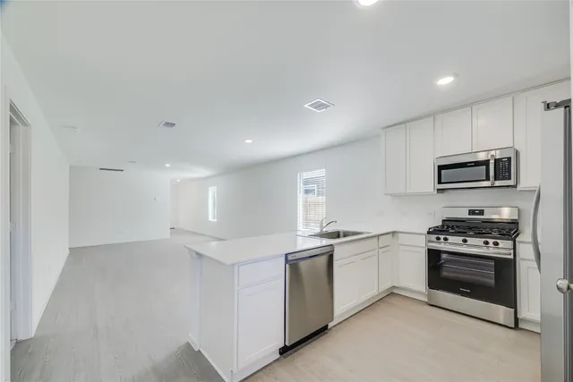 a kitchen with stainless steel appliances a sink stove and white cabinets