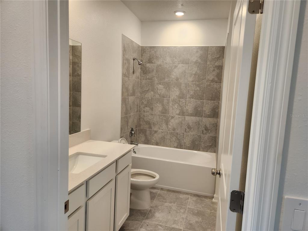 203 Bogey Drive Davenport, FL 33896 - Photo 35 of 41 a bathroom with a granite countertop sink a toilet and shower