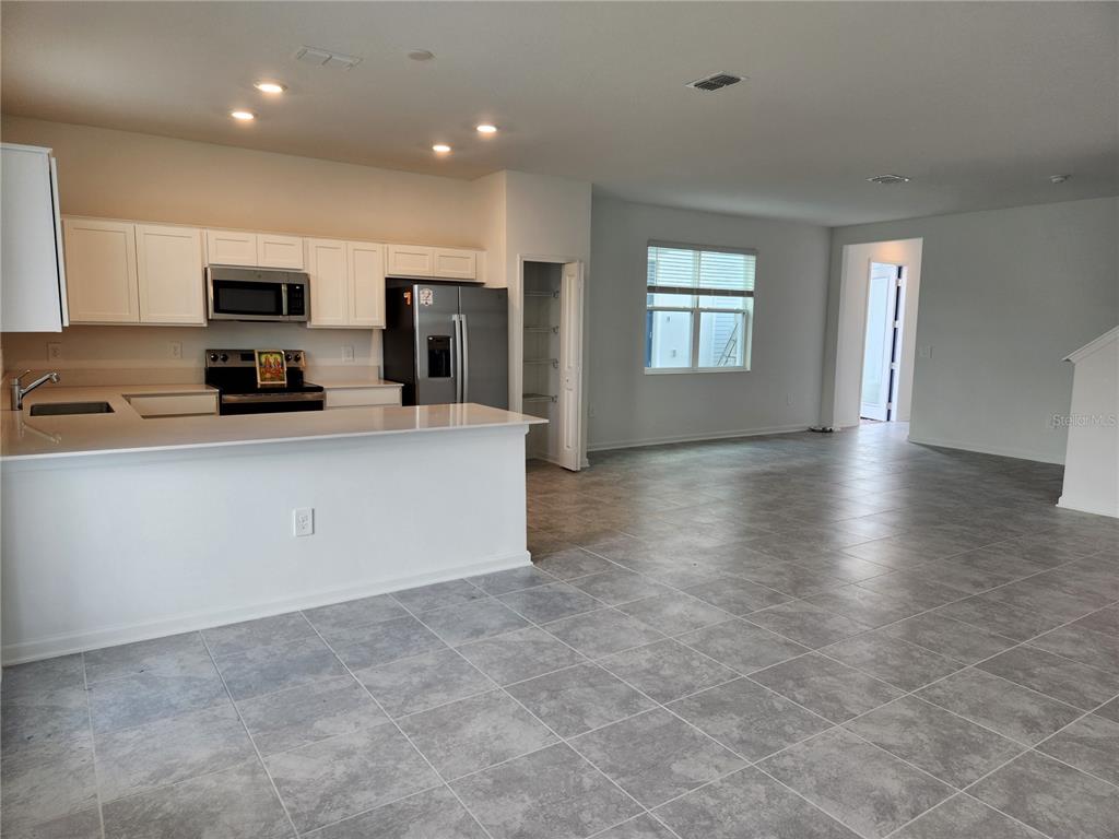 203 Bogey Drive Davenport, FL 33896 - Photo 8 of 41 a large kitchen with stainless steel appliances a large counter top and a stove