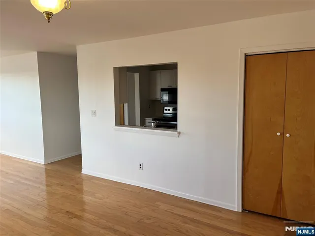 a view of an empty room with wooden floor and closet