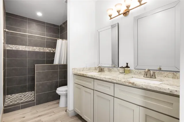 a bathroom with a double vanity sink toilet and shower