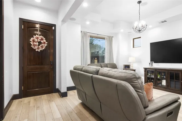 a living room with furniture a flat screen tv and a chandelier