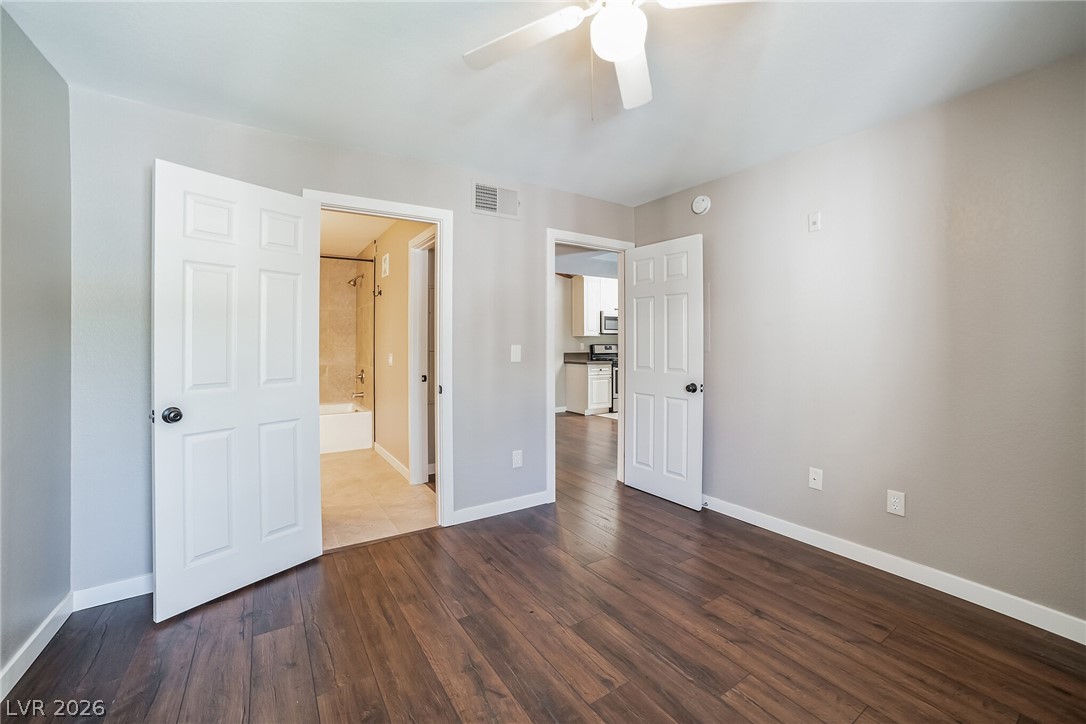 7885 West Flamingo Road, Unit 2041 Las Vegas, NV 89147 - Photo 12 of 14 Unfurnished bedroom with dark wood finished floors, ensuite bathroom, and a ceiling fan