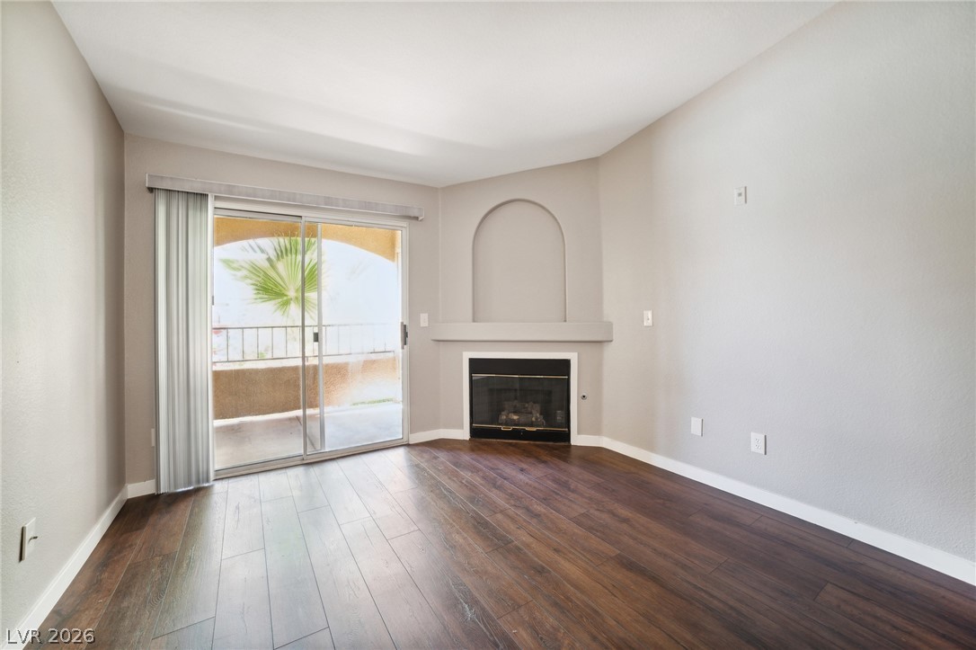 7885 West Flamingo Road, Unit 2041 Las Vegas, NV 89147 - Photo 2 of 14 Unfurnished living room featuring dark wood-style flooring and a glass covered fireplace