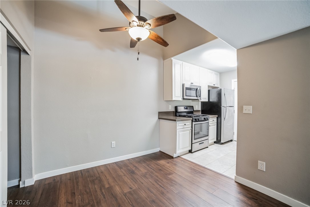 7885 West Flamingo Road, Unit 2041 Las Vegas, NV 89147 - Photo 3 of 14 Kitchen featuring white cabinetry, stainless steel appliances, dark wood-style flooring, and a ceiling fan