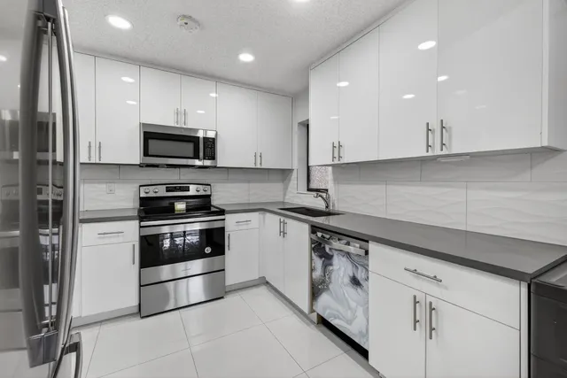 a kitchen with granite countertop white cabinets and stainless steel appliances