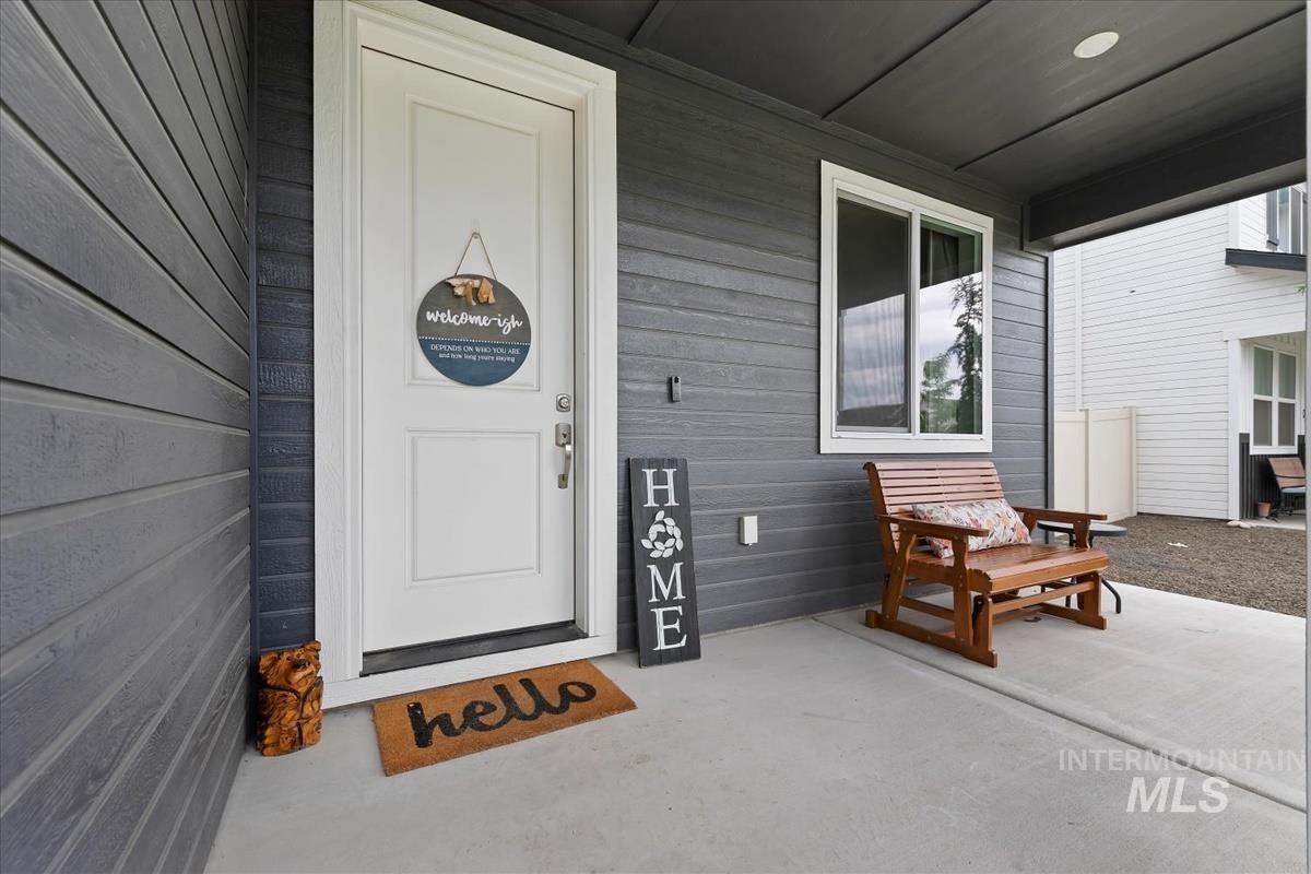 815 Knowledge Street Middleton, ID 83644 - Photo 42 of 49 Covered front porch featuring a white entry door, dark gray horizontal siding, an overhead recessed light, and a white-framed window